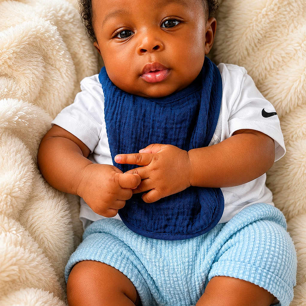 Ishmael is registered to the contest to win money with this photo: baby, infant, child, curly_hair, blue_bib, white_shirt, blue_shorts, grey_socks, fluffy_blanket, soft_texture, cute, portrait, indoors, comfortable, relaxed, chubby_arms, chubby_legs, looking_at_camera, skin, hands