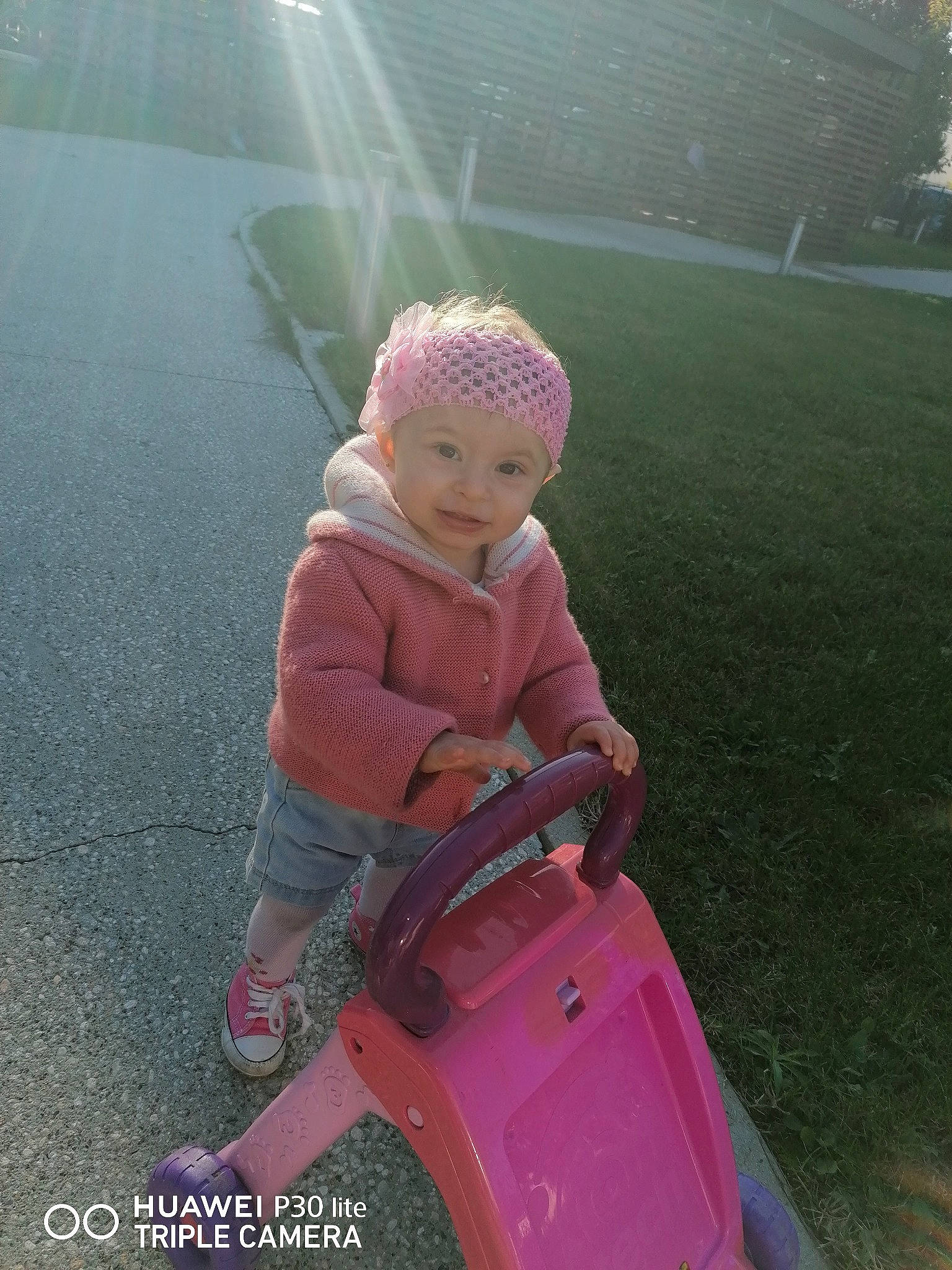 Nellya participe au concours pour gagner de l'argent avec cette photo : asphalt, automotive_design, baby, bumper, cap, eye, face, fun, grass, hat, headwear, leg, leisure, motor_vehicle, person, personal_protective_equipment, pink, recreation, riding_toy, toddler