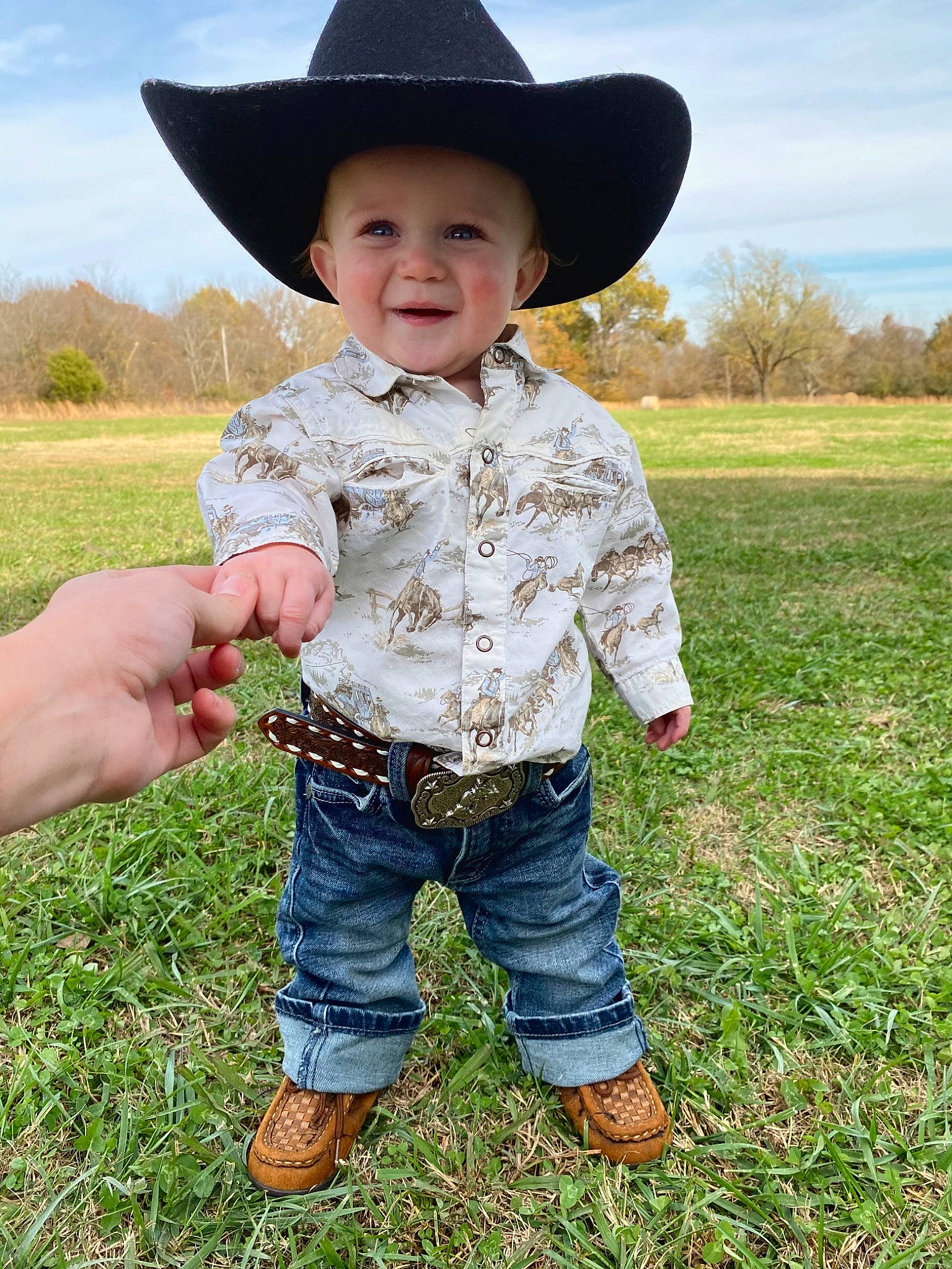 Kohen is registered to the contest to win money with this photo: baby_toddler_clothing, cloud, eye, face, facial_expression, gesture, grass, grassland, happy, hat, headgear, headwear, jeans, outerwear, people_in_nature, person, photograph, sky, sleeve, smile