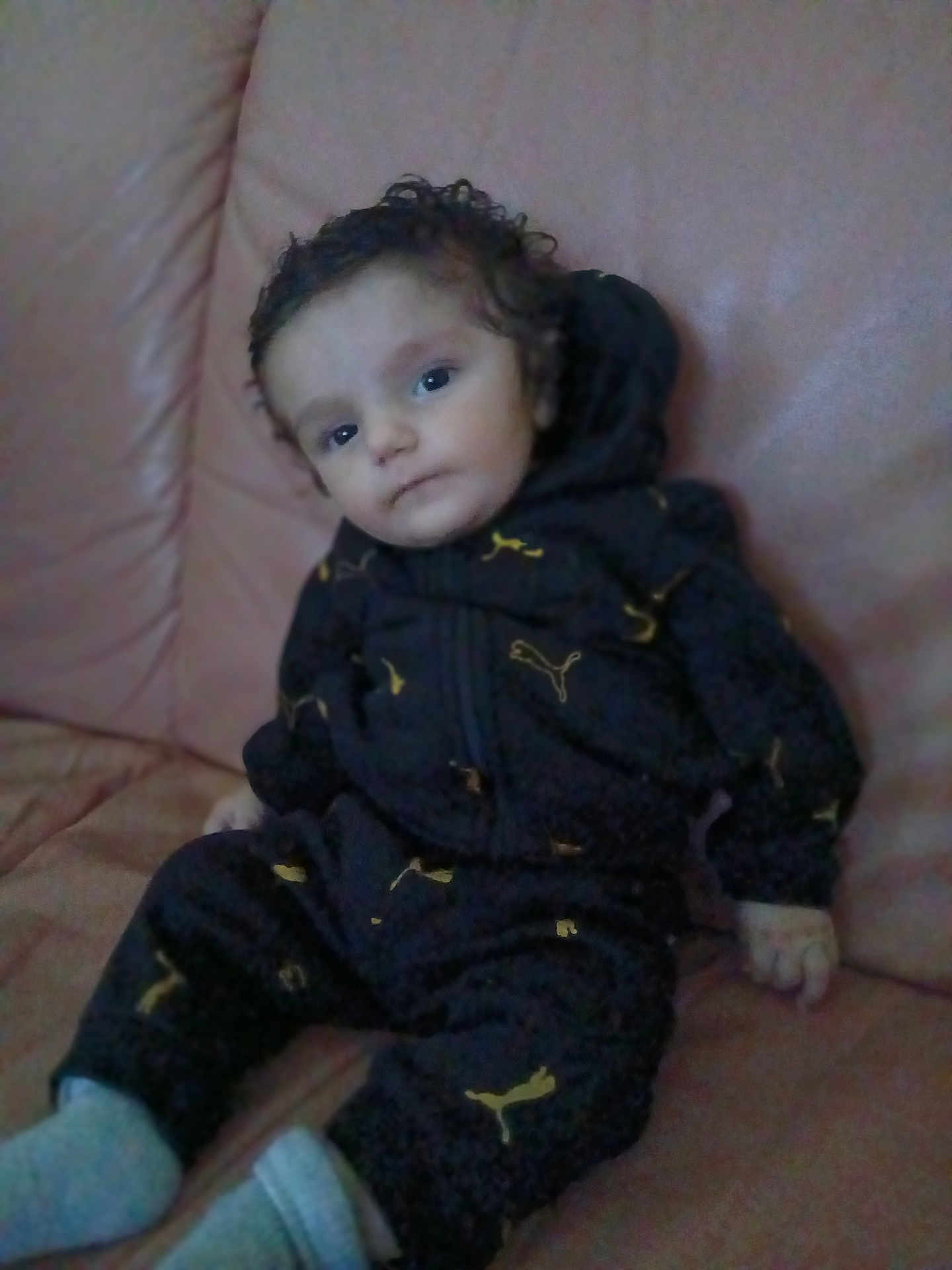Flavio participe au concours pour gagner de l'argent avec cette photo : child, baby, curly_hair, black_outfit, puma_logo, sitting, couch, indoor, calm, portrait, young_child, clothing, footwear, person, face, head, looking, casual, comfortable, home