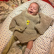 Joshua participe au concours pour gagner de l'argent avec cette photo : baby, smile, infant, blanket, cushion, star_pattern, fuzzy_clothing, duck_emblem, cozy, lying_down, happy, indoors, fabric, sock, child, cute, soft_texture, resting, comfort, warm