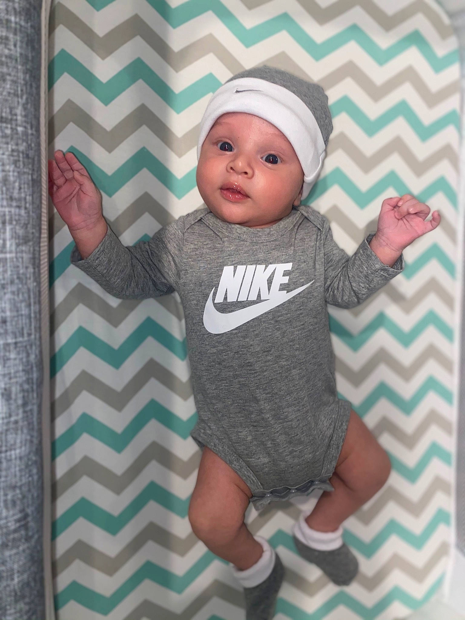 Chandler is registered to the contest to win money with this photo: baby, baby_products, baby_toddler_clothing, brick, cap, cheek, child, finger, gesture, happy, headwear, linens, magenta, pattern, person, pink, room, sleeve, t_shirt, textile