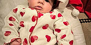 Alba participe au concours pour gagner de l'argent avec cette photo : baby, infant, santa_hat, onesie, red_hearts, cushion, soft_toy, holiday, festive, cute, portrait, indoor, child, face, clothing, cozy, smile, holiday_season, young, celebration
