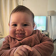 Alba a rejoint le concours — aidez-le/la à gagner de superbes lots ! baby, child, face, smile, tongue, sweater, clothing, indoor, curtains, lamp, furniture, person, portrait, hands, cute, happy, infant, young_child, cozy, room