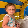 Lya participe au concours pour gagner de l'argent avec cette photo : child, toddler, playground, play_structure, sand, blue_eyes, smiling, tongue_out, colorful, yellow, blue, sleeveless_shirt, shorts, curly_hair, fun, outdoor, summer, play, happy, cute
