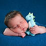 baby, sleeping, plushie, dinosaur, soft_toy, blue, blanket, cozy, infant, cute, child, peaceful, resting, portrait, closeup, hand, face, skin, hair, indoor