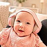 baby, infant, headphones, pink, smile, cute, face, portrait, child, indoors, bib, soft_lighting, happy, young_child, apparel, sitting, technology, headwear, cozy, blurred_background