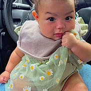 Alandra joined the competition — help win amazing prizes! baby, child, infant, sitting, car_interior, steering_wheel, green_dress, daisies, bib, curious, hand, legs, cute, rosy_cheeks, person, seat, lap, clothing, indoor, portrait