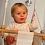 toddler, child, indoor, swing, rope, blonde_hair, blue_eyes, clothing, neutral_background, expression, hand, seat, rope_swing, person, portrait, young_child, curious, casual, soft_lighting, cozy