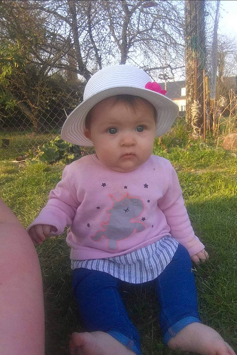 Lilie-rose a rejoint le concours — aidez-le/la à gagner de superbes lots ! baby, baby_toddler_clothing, cap, child, eye, face, fun, grass, happy, hat, leisure, people_in_nature, person, pink, plant, recreation, skin, sun_hat, thigh, toddler