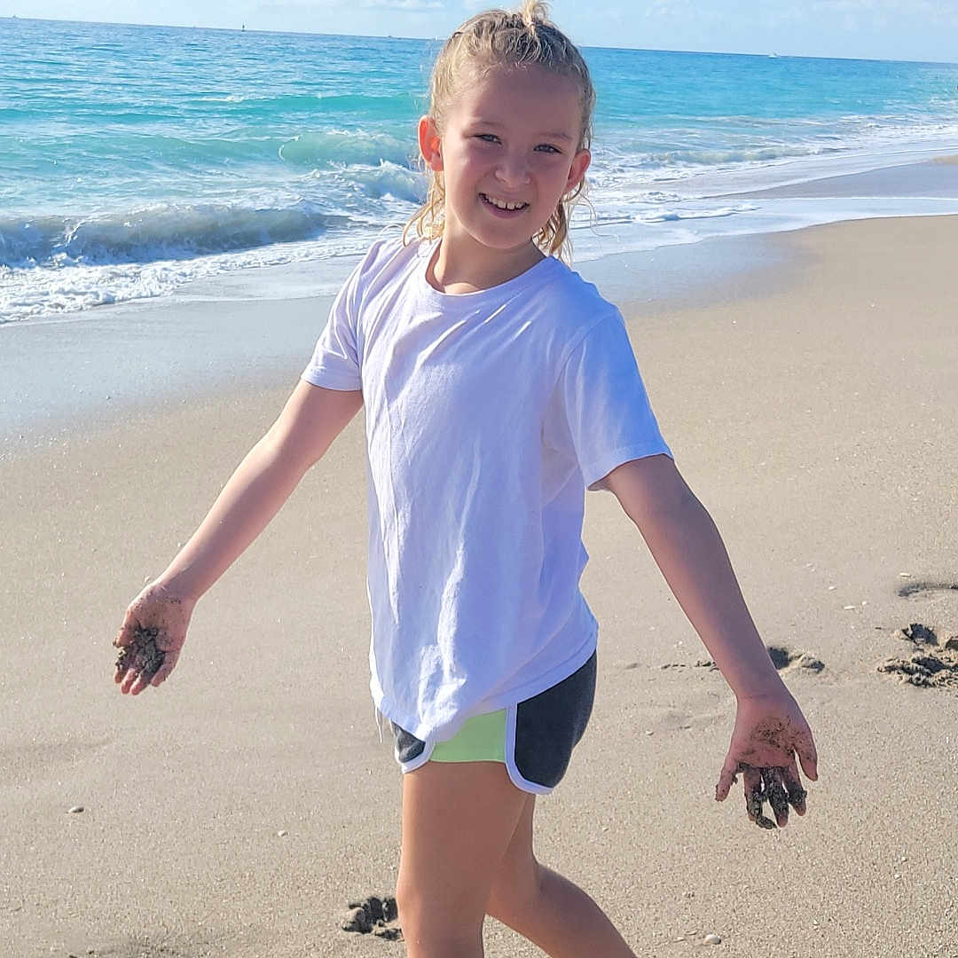 Madelynn is registered to the contest to win money with this photo: beach, beachwear, child, clothing, coast, face, female, girl, head, nature, outdoors, person, photography, portrait, sea, shoreline, shorts, summer, t_shirt, water