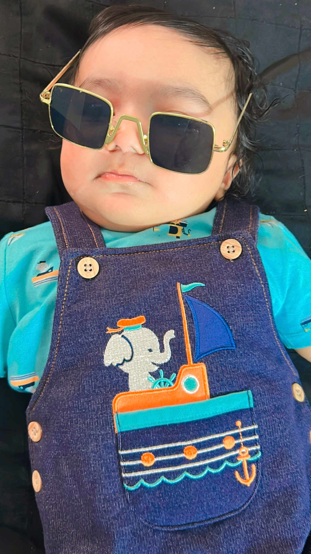 Aarvik joined the competition — help win amazing prizes! baby, child, sunglasses, denim, overall, elephant, boat, patch, clothing, cute, portrait, face, infant, blue, orange, buttons, lying_down, indoor, serious, fashion