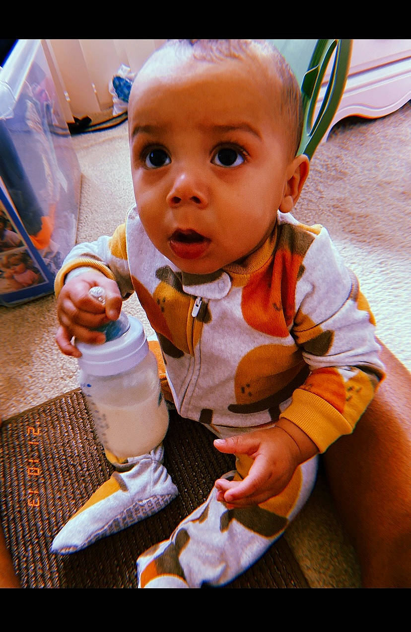 Garrett is registered to the contest to win money with this photo: baby, baby_products, baby_toddler_clothing, cheek, child, finger, flooring, fun, happy, iris, nose, orange, person, play, room, sitting, skin, sleeve, surprise, thumb