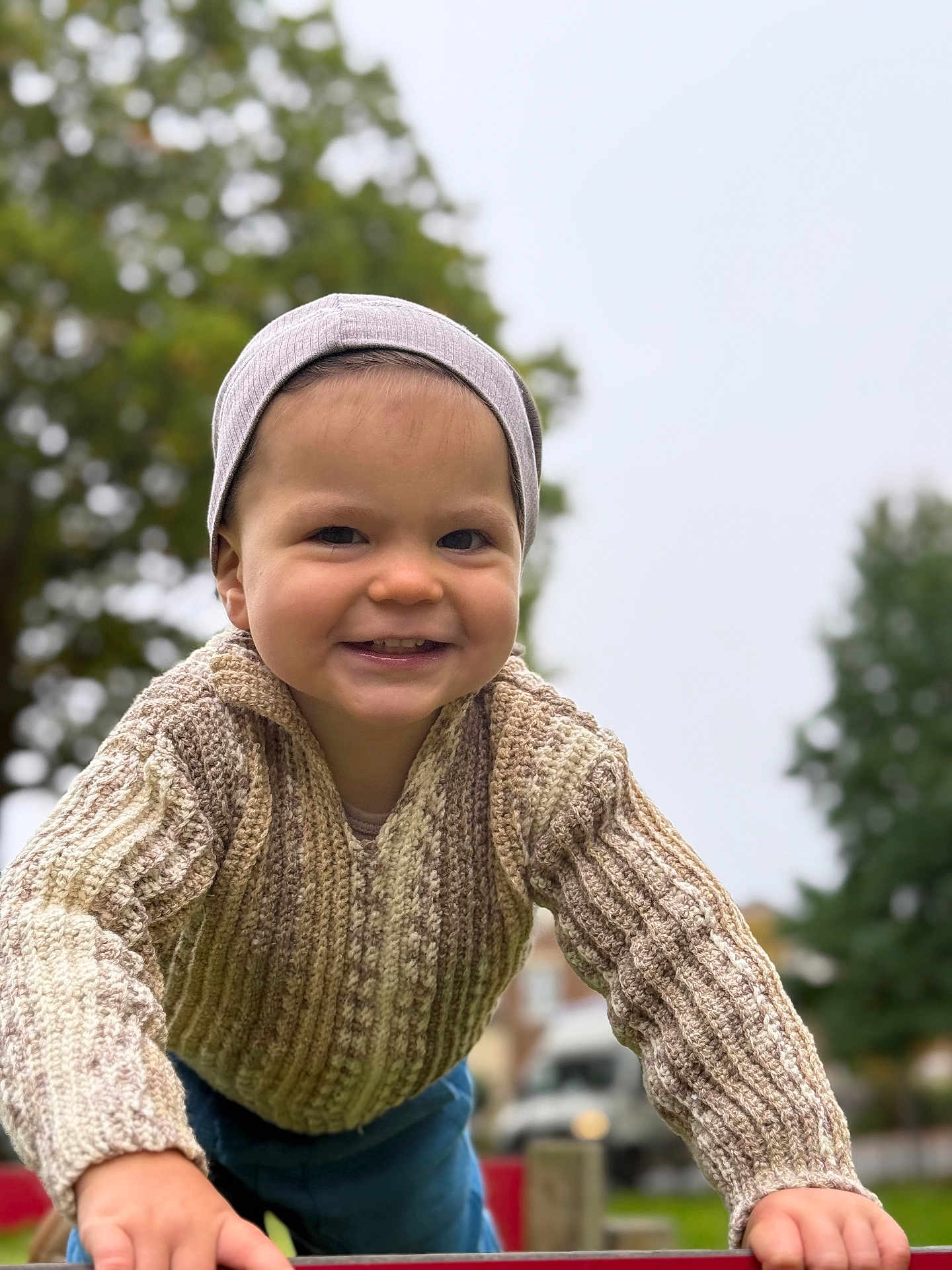 Tyson joined the competition — help win amazing prizes! beanie, blurred_background, casual_clothing, child, curious, cute, daylight, face, fall, happy, knitted_sweater, nature, outdoor, person, playground, portrait, smiling, toddler, trees, young_child