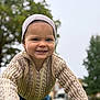 Tyson is registered to the contest to win money with this photo: beanie, blurred_background, casual_clothing, child, curious, cute, daylight, face, fall, happy, knitted_sweater, nature, outdoor, person, playground, portrait, smiling, toddler, trees, young_child