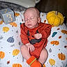 Fletcher is registered to the contest to win money with this photo: baby, newborn, sleeping, infant, child, portrait, orange_outfit, pumpkin, halloween, blanket, cozy, number_block, plush_toy, indoor, lying_down, closed_eyes, hand, socks, seasonal, photography
