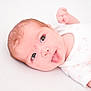 baby, infant, tongue_out, white_clothing, onesie, lying_down, cute, playful, skin, face, head, arm, newborn, child, small_hand, expression, soft_light, closeup, indoors, person