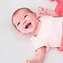 baby, infant, smiling, happy, lying_down, blanket, pink, clothing, face, skin, arm, hand, newborn, cute, child, soft_texture, closeup, portrait, expression, light_background