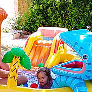 Maëlys participe au concours pour gagner de l'argent avec cette photo : ball, blue, child, fun, grass, green, happy, inflatable, outdoor, person, play, pool_toy, shark, slide, smile, summer, toy, trees, water, yellow