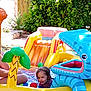 ball, blue, child, fun, grass, green, happy, inflatable, outdoor, person, play, pool_toy, shark, slide, smile, summer, toy, trees, water, yellow