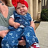 baby, child, red_bow, headband, denim, floral, outdoor, building, sidewalk, adult, person, shoe, sneakers, cute, tongue, holding, casual, greenery, portrait, smile