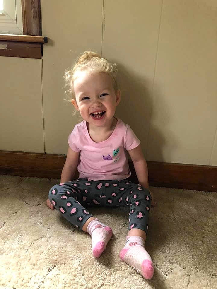 Skylin is registered to the contest to win money with this photo: baby, cheek, child, face, facial_expression, floor, flooring, footwear, head, joint, joy, leg, nose, person, pink, play, shoe, sitting, skin, smile