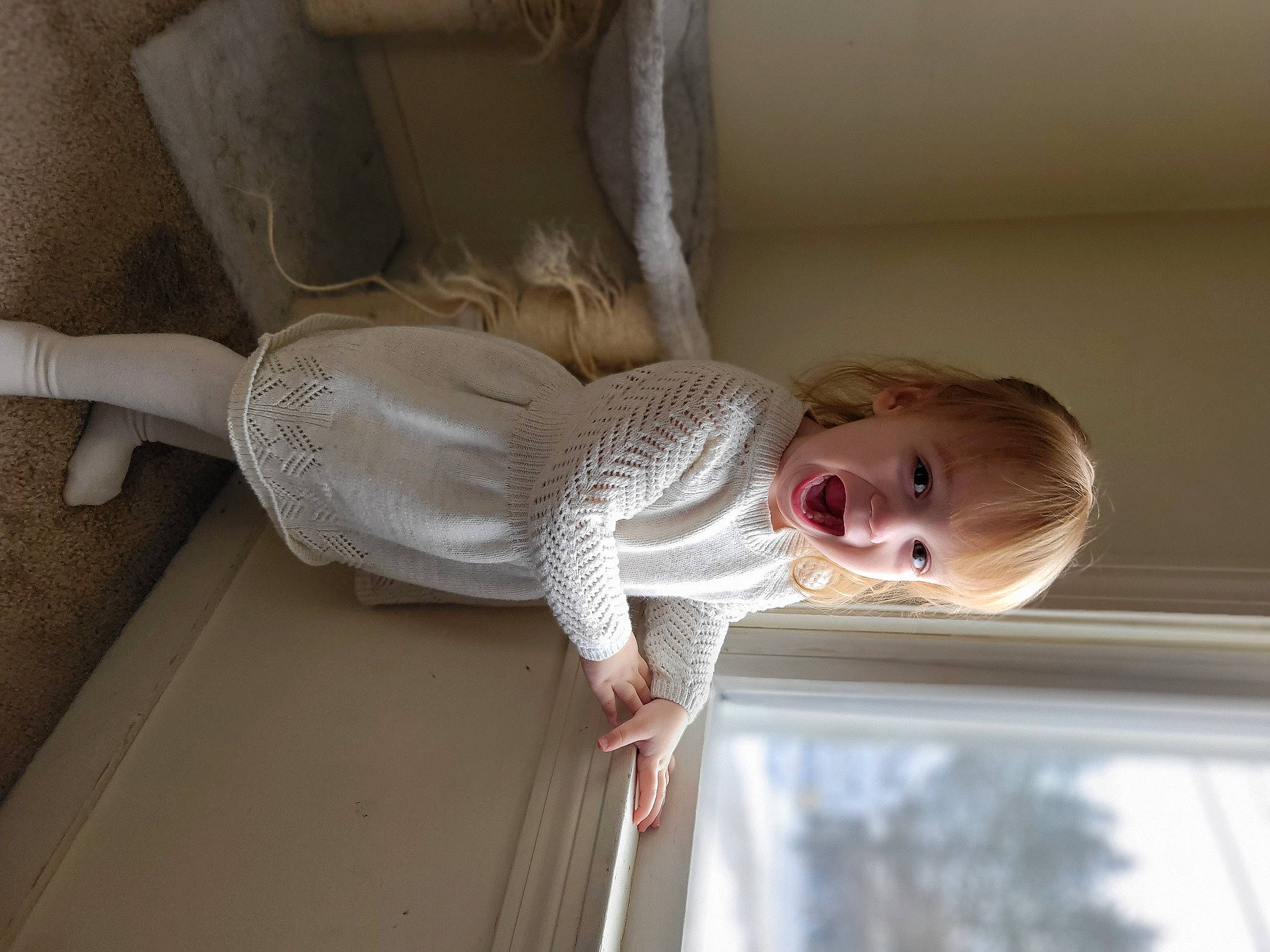 Peyton is registered to the contest to win money with this photo: baby, child, comfort, door, elbow, flooring, fun, happy, hardwood, human_body, linens, person, room, sitting, smile, toddler, tree, window, wood