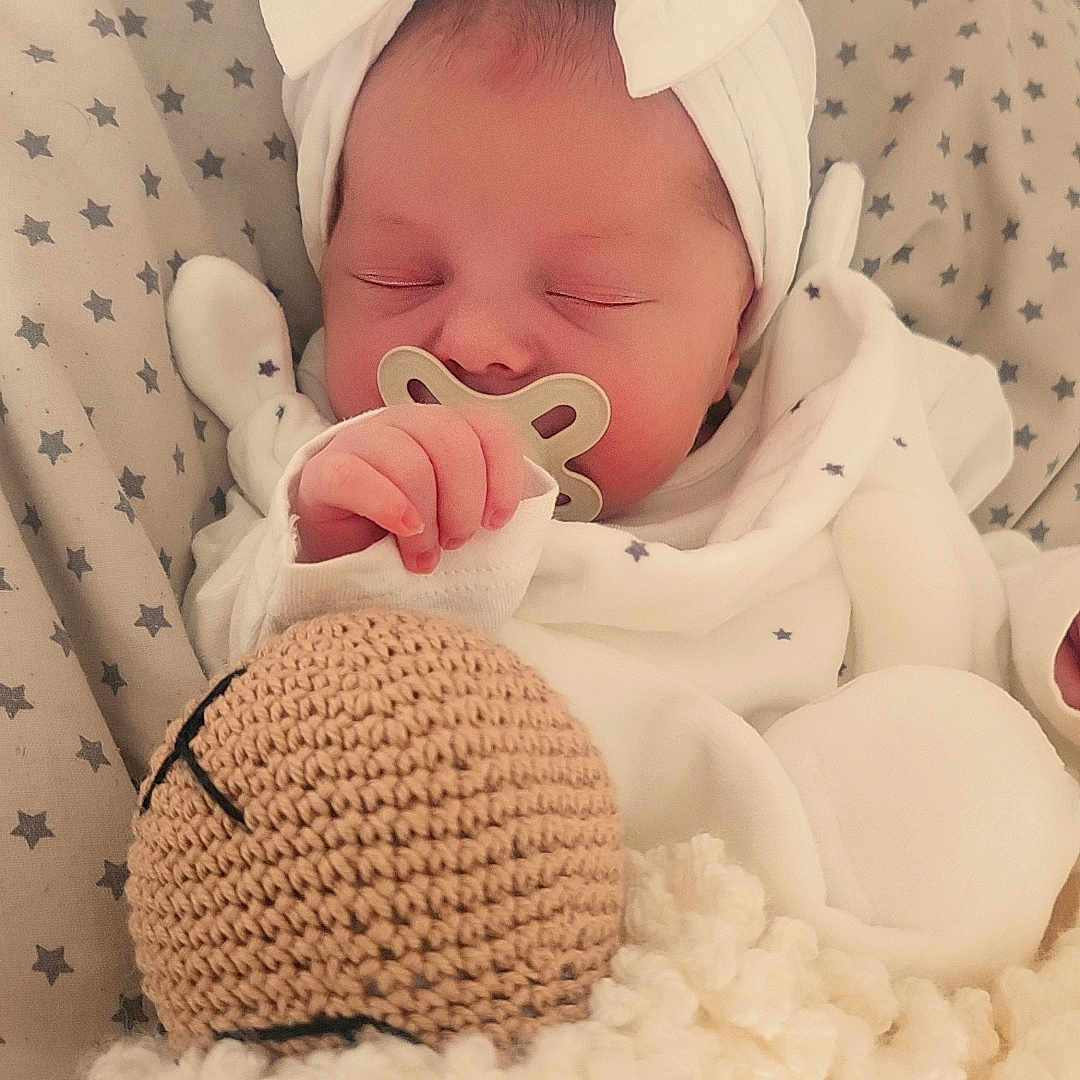 Mya a rejoint le concours — aidez-le/la à gagner de superbes lots ! baby, blanket, bow, child, closeup, cozy, cute, face, hand, headband, indoors, infant, knitted_doll, newborn, pacifier, resting, sleeping, soft_toy, star_pattern, white_clothing