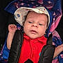 baby, blanket, bright_colors, car_seat, child, closeup, clothing, eyes, face, hand, hat, hearts, indoors, infant, person, portrait, red_shirt, seatbelt, stars, straps