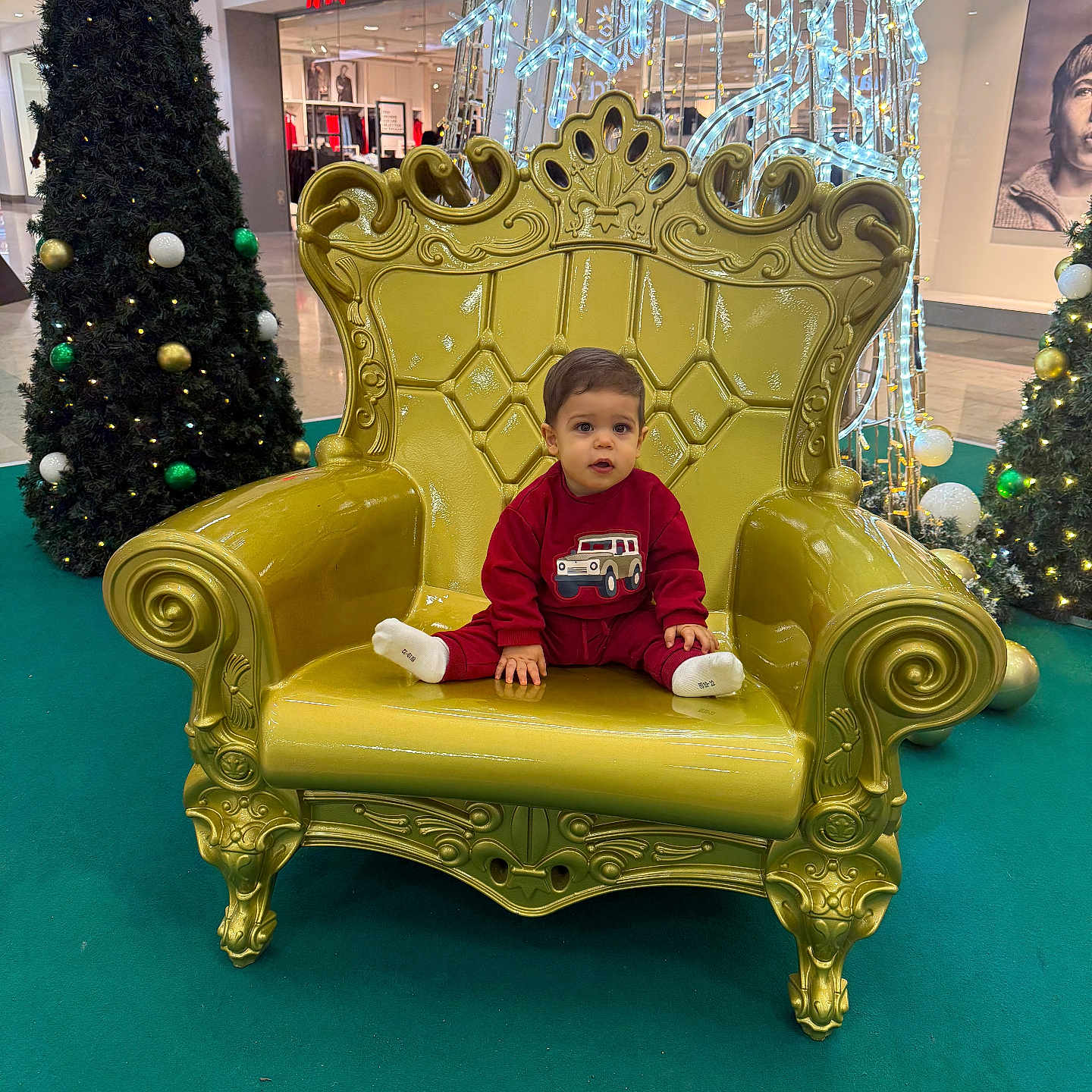 Mattéo Cristiano participe au concours pour gagner de l'argent avec cette photo : carpet, child, christmas_trees, decorations, expression, face, festive, golden_chair, holiday_lights, holiday_season, indoor, mall, ornate_chair, portrait, red_clothing, seated, shopping, toddler, toy_car_image, winter