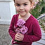 bench, casual_clothing, child, concrete_wall, cute, daylight, earrings, flowers, girl, greenery, happy, long_sleeve_shirt, maroon_shirt, nature, outdoor, pants, pink_flowers, portrait, smile, young