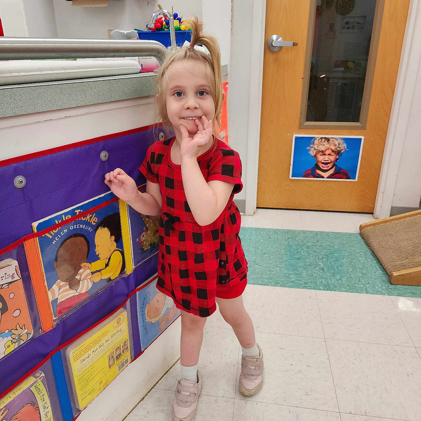 Haley joined the competition — help win amazing prizes! child, girl, red_dress, checkered_pattern, classroom, books, floor_tiles, door, indoor, playful, curious, sneakers, white_socks, hand_on_face, colorful, educational, young_child, smiling, standing, hair_tied