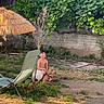 boy, dog, grass, outdoor, backyard, sunny, greenery, lounge_chair, umbrella, tree, fence, smiling, shirtless, pet, summer, nature, relaxation, playing, child, animal