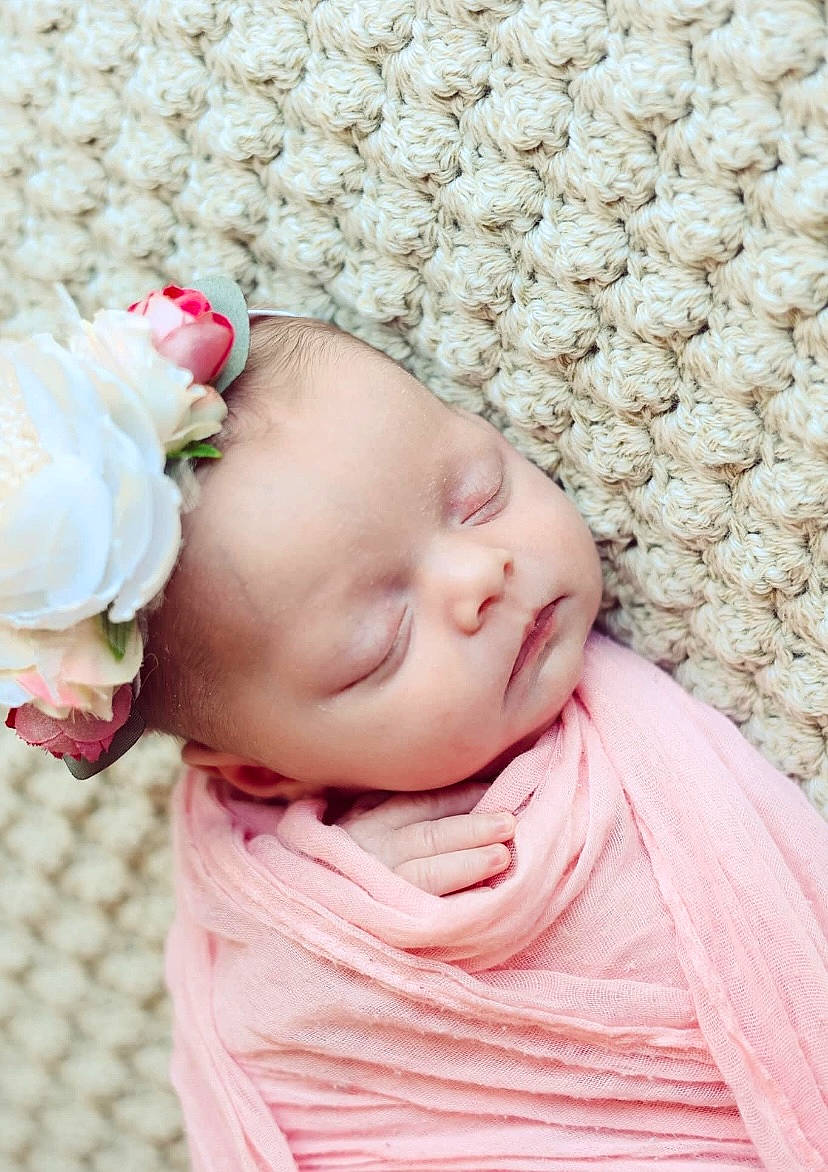 Ellie is registered to the contest to win money with this photo: baby, baby_toddler_clothing, cheek, chin, collar, comfort, flower, grass, headgear, linens, lip, pattern, peach, person, petal, pink, rose, skin, sleeve, textile
