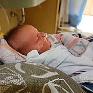 Iris is registered to the contest to win money with this photo: newborn, baby, infant, sleeping, blanket, hospital, medical, oxygen_tube, nasal_cannula, bed, resting, cozy, soft_focus, indoor, person, child, healthcare, care, pediatric, peaceful