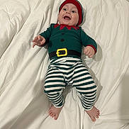 Sasha a rejoint le concours — aidez-le/la à gagner de superbes lots ! baby, child, infant, smiling, happy, lying_down, bed, blanket, striped_pants, costume, elf, hat, feet, cute, clothing, indoors, person, face, headwear, playful