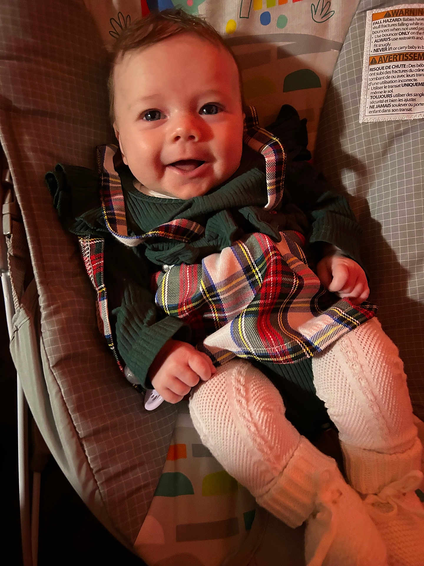 Kylah joined the competition — help win amazing prizes! baby, baby_rocker, child, clothing, cushion, cute, face, footwear, hand, happy, indoor, infant, knitted_tights, person, plaid, portrait, seated, smiling, toddler, warm_lighting