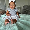 Scarlett is registered to the contest to win money with this photo: toddler, child, baby, headband, bow, striped_clothing, floral_skirt, bed, quilt, indoor, room, door, crib, blanket, furniture, person, cute, portrait, sitting, barefoot