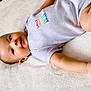 baby, child, infant, smile, onesie, clothing, skin, face, arm, hand, blanket, soft, lying_down, cute, young, portrait, indoor, peaceful, relaxed, comfort