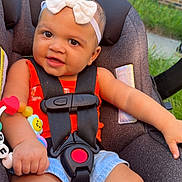 Taliyah joined the competition — help win amazing prizes! baby, bow_headband, bracelet, brick_wall, car_seat, child, close_up, denim_shorts, earring, greenery, happy, infant, outdoor, photography, portrait, red_outfit, safety_harness, sitting, smiling, toy