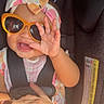 Taliyah joined the competition — help win amazing prizes! baby, child, infant, car_seat, passenger, sunglasses, headband, bow, hand, smiling, open_mouth, portrait, indoors, vehicle, car_interior, seatbelt, buckled, fashion, colorful_clothing, road_trip