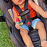 Taliyah is registered to the contest to win money with this photo: baby, bare_feet, bow, car_seat, child, colorful_toy, daylight, denim_shorts, grass, harness, headband, infant, outdoor, park, photography, portrait, red_outfit, sitting, smiling, toy