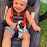 baby, baby_feet, bow, car_seat, child, denim_shorts, garden, grass, happy, harness, headband, infant, outdoor, portrait, red_shirt, sitting, smiling, sunlight, teething_toy, toy