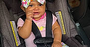 Taliyah is registered to the contest to win money with this photo: baby, child, infant, smiling, car_seat, seatbelt, bow, floral_clothing, pink_shirt, patterned_pants, portrait, sitting, indoors, vehicle, safety_harness, fashion, hand_to_mouth, happy, closeup, photography
