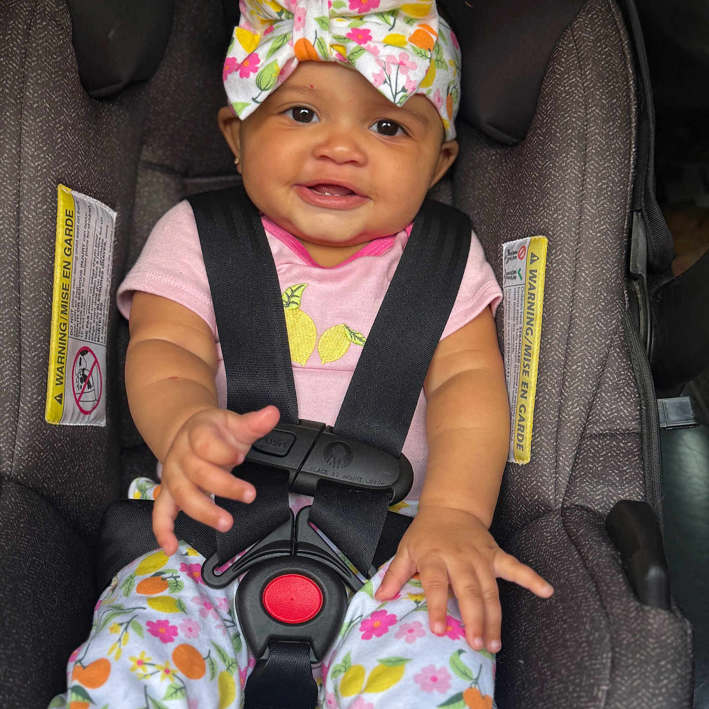 Taliyah is registered to the contest to win money with this photo: baby, infant, child, smiling, portrait, car_seat, harness, floral_bow, headband, pink_clothing, patterned_clothing, floral_pattern, fruit_pattern, sitting, indoors, vehicle, automobile,  안전, close_up, happy