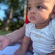 Taliyah is registered to the contest to win money with this photo: baby, child, infant, portrait, outdoor, nature, trees, bokeh, sunlight, close_up, face, eyes, curious, sitting, white_shirt, short_sleeves, diaper, barefoot, drool, photography