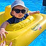 baby, child, sunglasses, hat, swimwear, inflatable_float, pool, water, summer, outdoor, hand, sunny, blue, yellow, relaxing, vacation, leisure, swimming, floating, sunhat