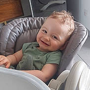 Noé a rejoint le concours — aidez-le/la à gagner de superbes lots ! appliance, baby, child, comfort, couch, curly_hair, face, floor, furniture, green_shirt, happy, high_chair, indoor, kitchen, modern, person, seat, smiling, toy, wooden_cabinet