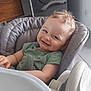 baby, child, high_chair, smiling, curly_hair, indoor, toy, green_shirt, face, furniture, kitchen, couch, wooden_cabinet, appliance, floor, modern, happy, person, seat, comfort