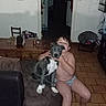 child, puppy, dog, hugging, sitting, armchair, indoors, home, living_room, tile_floor, gray_dog, white_chest, pet, companion, portrait, candid, flash_photography, furniture, barefoot, family